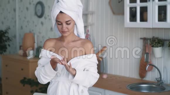 穿着浴衣头上戴着毛巾的女人在肩膀上涂上奶油动作缓慢视频的预览图