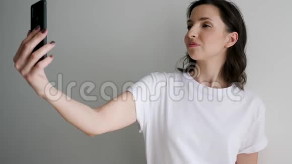 穿着白色t恤的女人在光墙上自拍视频的预览图