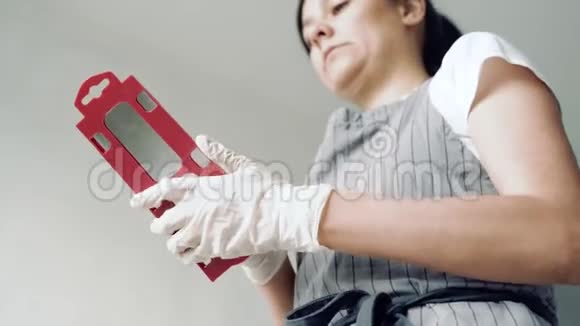 穿着围裙戴着手套的年轻女子在下班前从箱子里掏出一把铲子视频的预览图