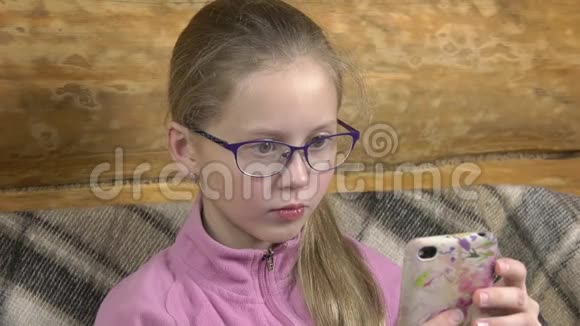 严肃的小女孩正在智能手机上看书视频的预览图