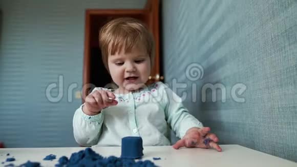 小女孩坐在儿童桌前慢动作地玩动能沙视频的预览图
