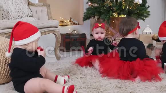 圣诞节概念小婴儿坐在地毯上在装饰好的工作室里玩圣诞玩具视频的预览图