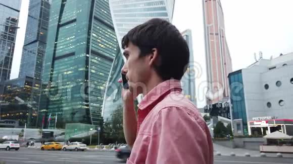 迷人的年轻商人在城市里走来走去讲手机视频的预览图