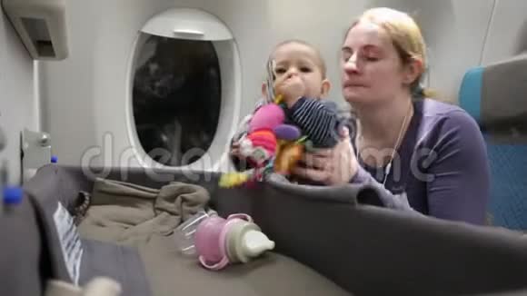 妈妈带着一个快乐的小孩在飞机上一个女人抱着一个婴儿她从一个特殊的摇篮里拿出一个玩具视频的预览图