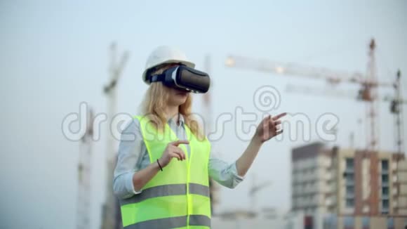一位女士戴着虚拟现实眼镜头盔和背心在建筑背景下控制着界面的手视频的预览图