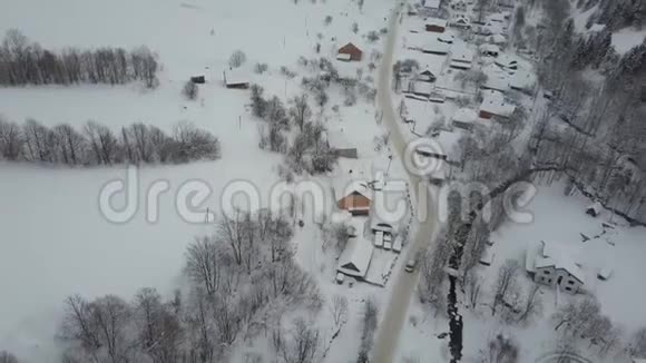 喀尔巴阡村冬季公路上行驶的汽车的鸟瞰图鸟雪覆盖的房子的视野农村视频的预览图