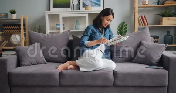 在漂亮的公寓里漂亮的女孩在家里轻松地读书视频的预览图