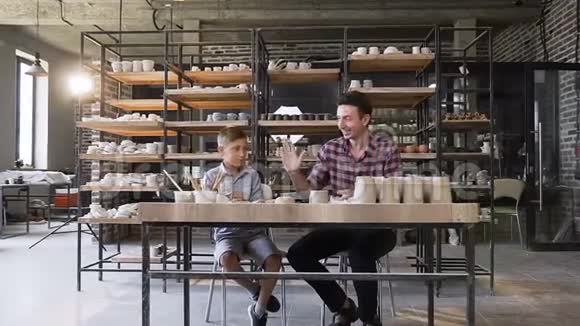 快乐的男孩和他的父亲揉捏陶罐的粘土视频的预览图