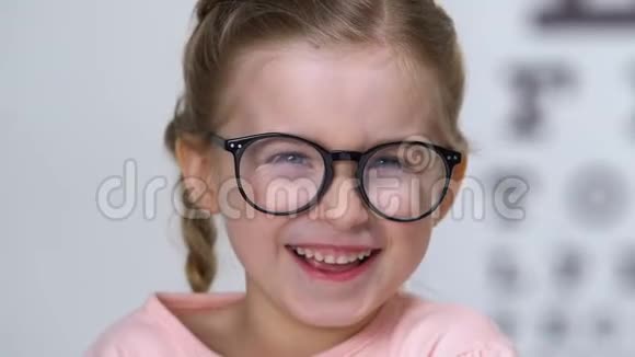 戴眼镜的快乐小女孩在相机眼科和健康上笑视频的预览图