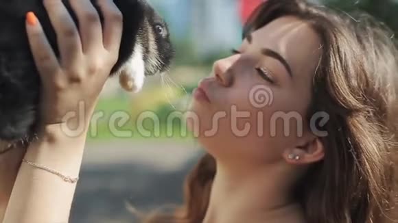 夏天年轻漂亮的女人在花园里抚摸和亲吻小毛兔特写视频的预览图