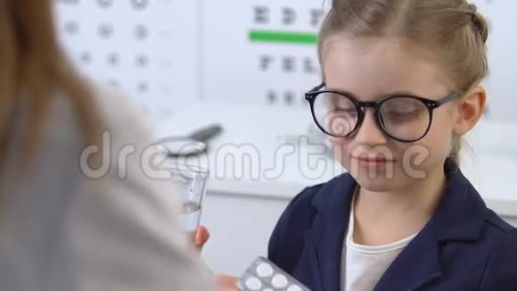 戴眼镜的小女孩在体检时用水吃药治疗视频的预览图