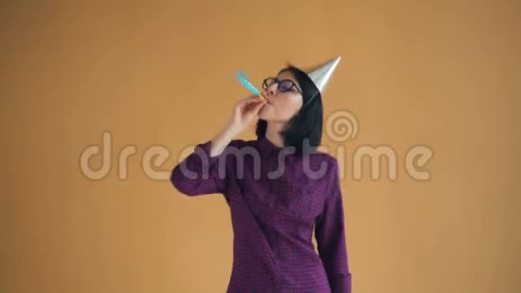 戴着生日帽的年轻女人吹着派对喇叭跳舞玩得很开心视频的预览图