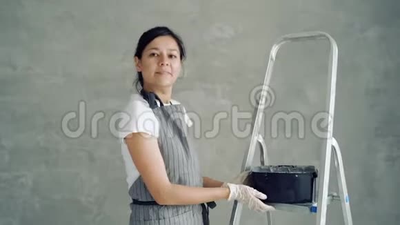 一个年轻的微笑女工的肖像展示一罐油漆或石膏建筑修理和翻新视频的预览图