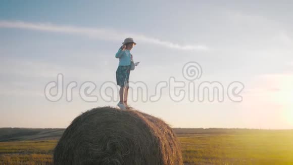 日落时干草跳跃的小女孩在乡下的干草堆附近的女孩视频的预览图