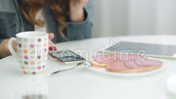 厨房早餐时用智能手机特写女人的手视频的预览图