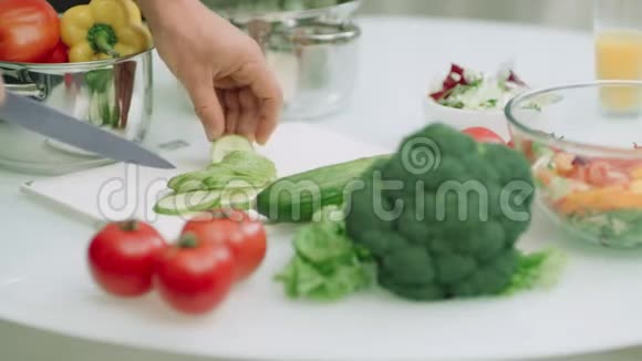 特写男人手慢慢地在厨房桌子上切黄瓜视频的预览图