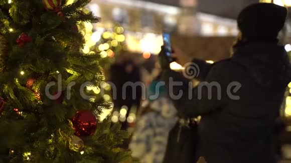 无法辨认的女孩在圣诞树上拍照透过新年树景色视频的预览图