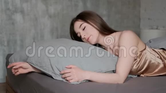一个年轻漂亮的黑发女人躺在床上睡觉睡觉时翻身伸展身体视频的预览图