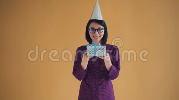 戴着明亮的派对帽戴着礼品盒和微笑的开朗年轻女士的肖像视频的预览图