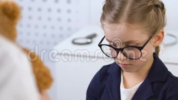 医生送泰迪熊给戴眼镜的小女病人儿童诊所服务视频的预览图