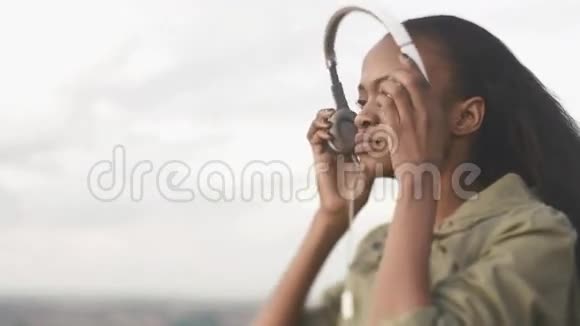 可爱的年轻非洲裔美国妇女听音乐在模糊的城市背景下放松视频的预览图