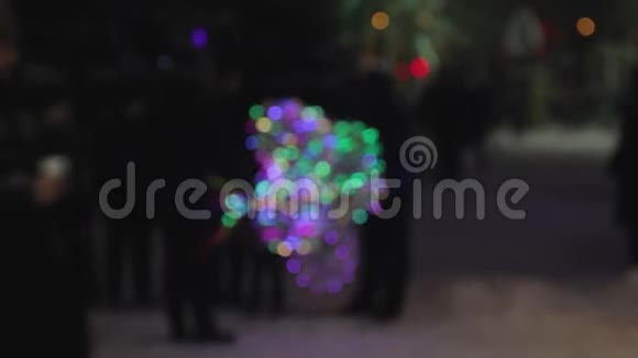 失去焦点模糊人们在冬天的晚上通过街头小贩的彩色发光二极管灯泡节日派对灯光秀视频的预览图