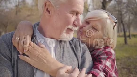 白种人幸福成熟家庭的特写肖像站在秋林的阳光下拥抱高级视频的预览图