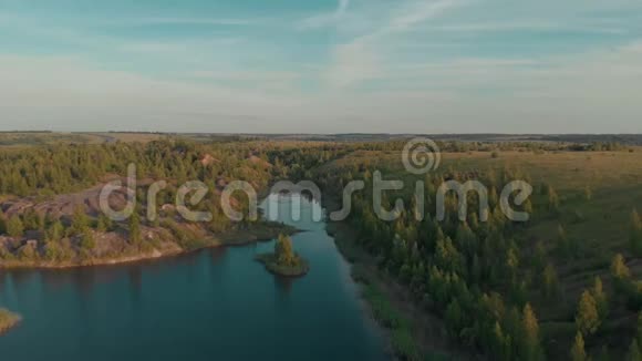 在一个被蓝色天空和白云的稀疏植被包围的小湖上飞行视频的预览图
