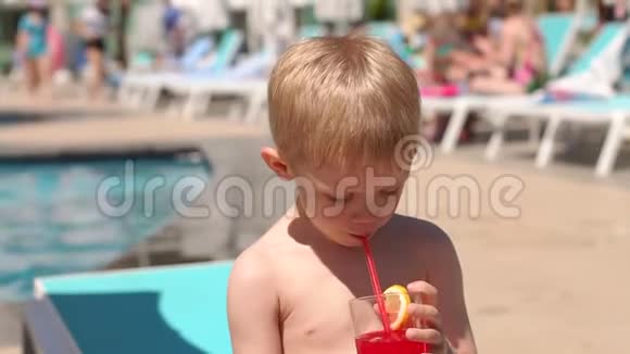 夏天一个金发小男孩在泳池边喝鸡尾酒视频的预览图