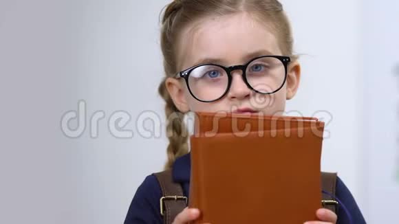 戴眼镜的可爱女学生拿着书需要知识天才视频的预览图