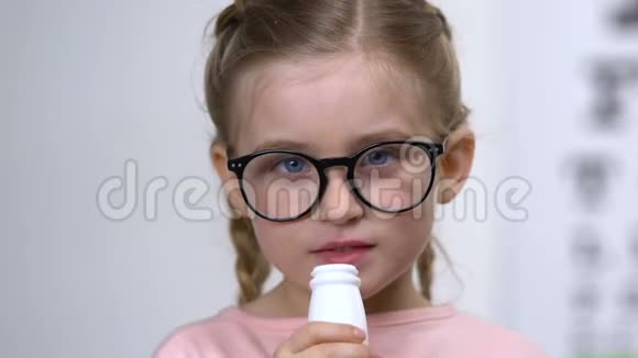可爱的戴眼镜的白种人女孩饮用奶瓶维生素饮料视频的预览图