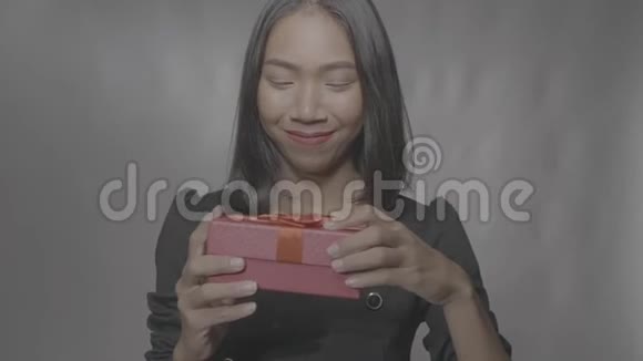 漂亮快乐的女孩打开礼物盒隔离在灰色的墙壁上视频的预览图