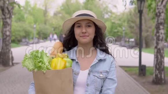 一位心情愉快的年轻美女走在城市公园的街上拿着一个大购物袋视频的预览图
