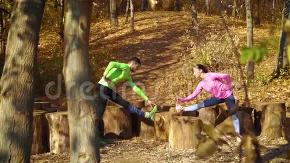 快乐的一对夫妇在秋天的森林里一起训练树桩视频的预览图