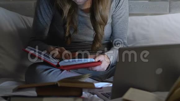 晚上有书和笔记本电脑的女学生考试准备教育视频的预览图