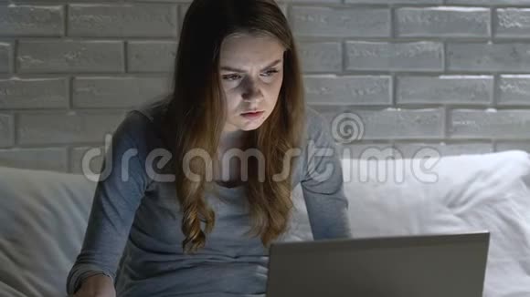 紧张的女孩用笔记本电脑晚上吃药在网上搜索诊断视频的预览图