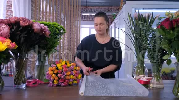 女花艺厂在花艺店剪纸包花花束视频的预览图
