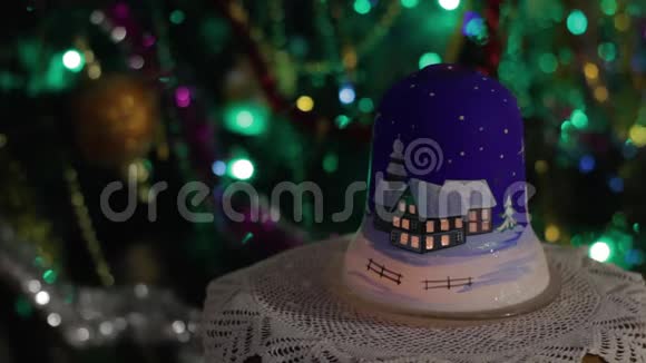 新年的灯在一棵装饰好的圣诞树的背景上放着一支蜡烛圣诞树上放着一个闪闪发光的花环鲜艳的灯光闪闪发光视频的预览图