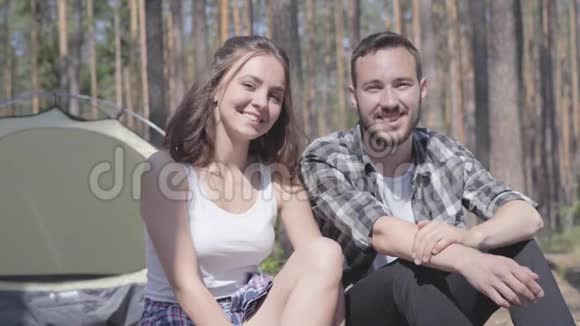 英俊的留胡子的年轻人和漂亮的年轻快乐的女人坐在旁边的肖像竖起大拇指可爱的一对视频的预览图