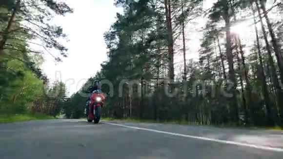 骑手正带着松树沿着马路骑自行车摩托车手驾驶他的摩托车视频的预览图