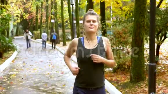 带耳机的运动女孩在秋季公园慢跑视频的预览图
