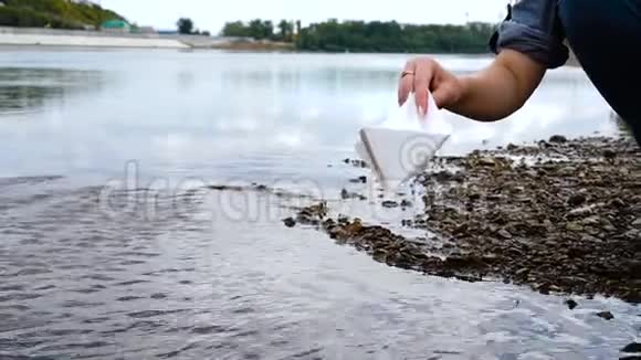 女人手把白纸船放在水面上推开它视频的预览图