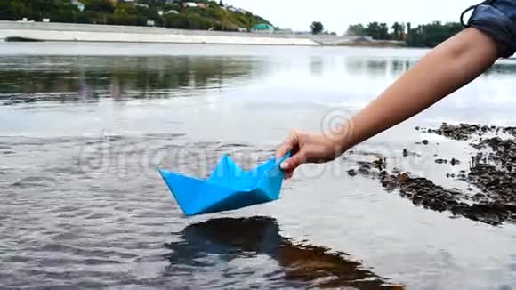 女人手把蓝色纸船放在水面上把它推开视频的预览图