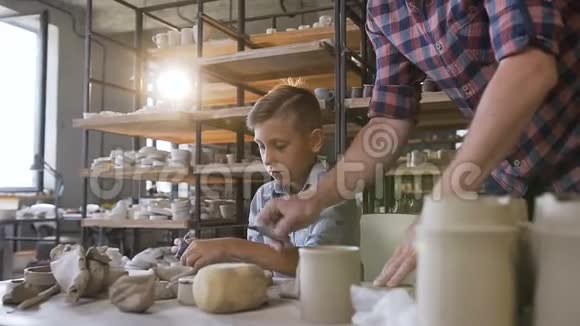 男性白种人陶工帮助他的儿子在花瓶上做图案视频的预览图