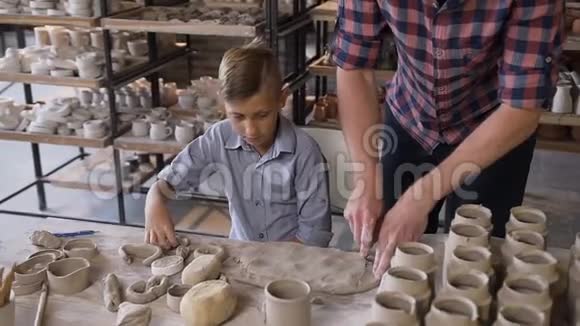 中年白种人父亲教小儿子如何在陶工轮上用粘土工作视频的预览图