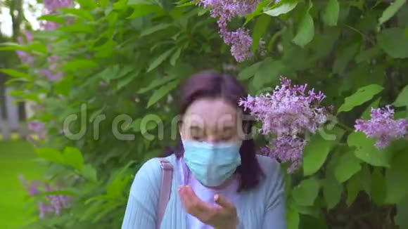 戴着医用口罩的年轻过敏妇女打喷嚏和看镜头的画像视频的预览图