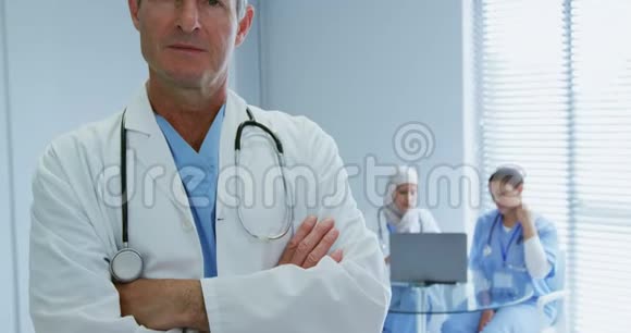 高加索男医生在医院交叉双臂站立的特写镜头视频的预览图