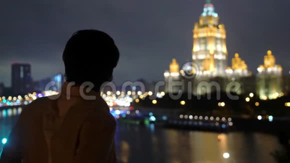 成功的年轻人站在阳台的城市天际线上莫斯科夜晚用美丽的波克看着城市的景色视频的预览图