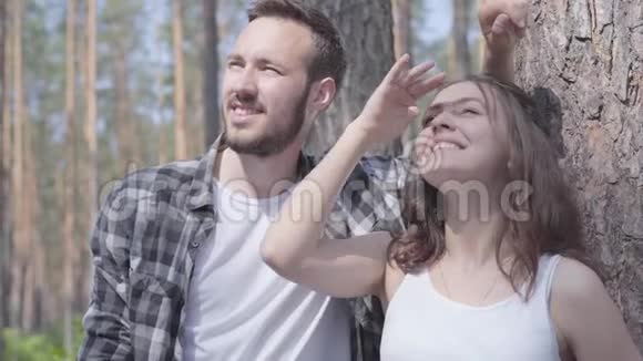 英俊的年轻人和漂亮的女人在松林里用手指向外看的肖像团结一致视频的预览图