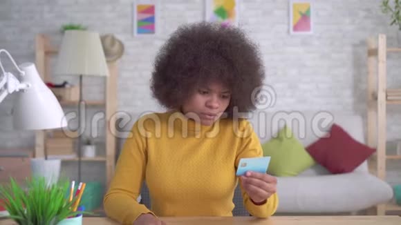 美国黑人妇女又累又压力大留着非洲发型看着他手中的银行卡哭着视频的预览图